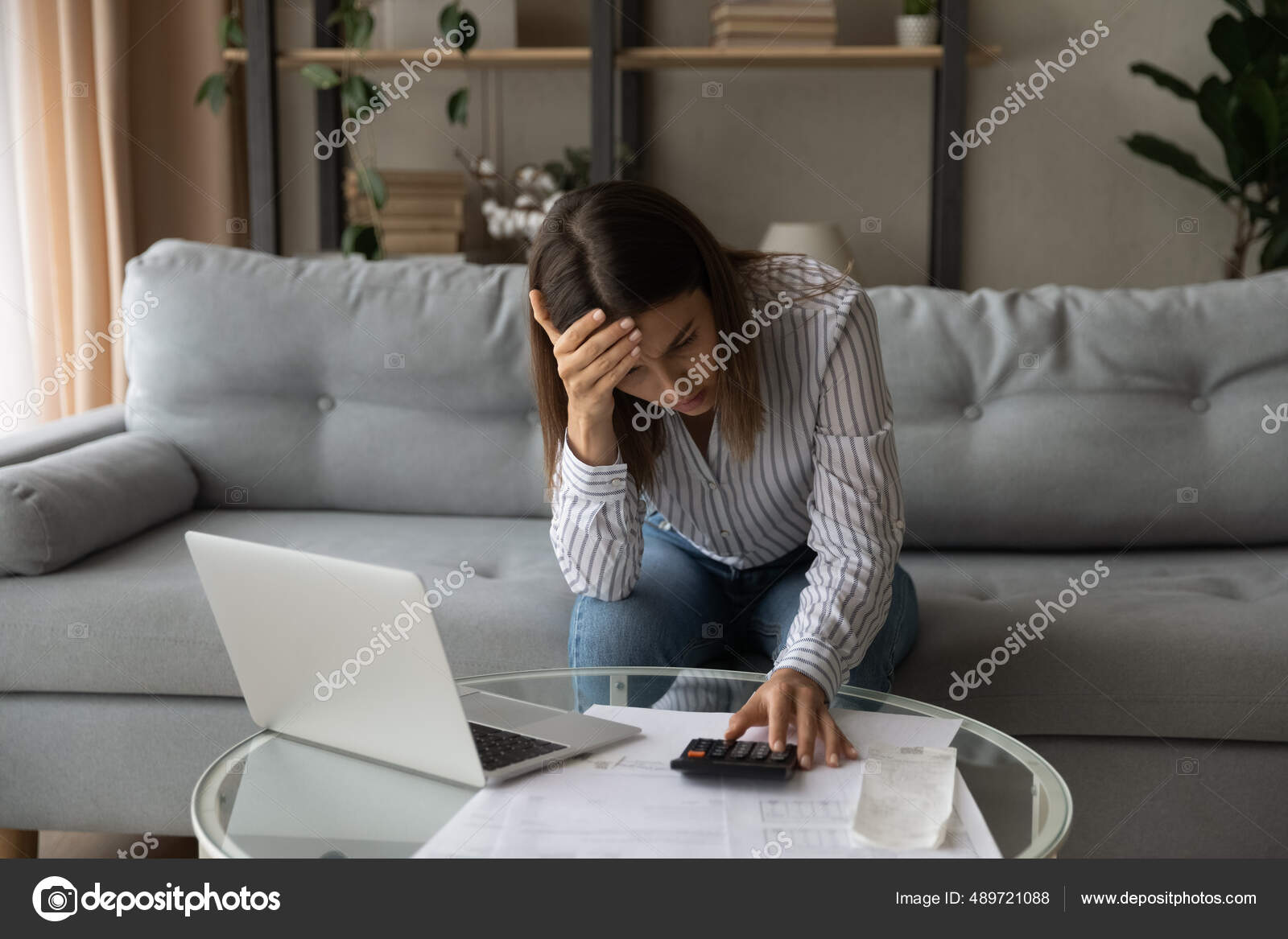 Desperate young woman sit on sofa at home calculates expenses feeling stressed about bank loan payments, lack of money, financial problems, thinking of unpaid taxes, bankruptcy, overdue bills concept